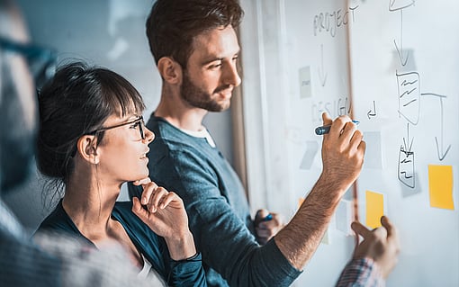 A group working on a problem and making notes on a board.