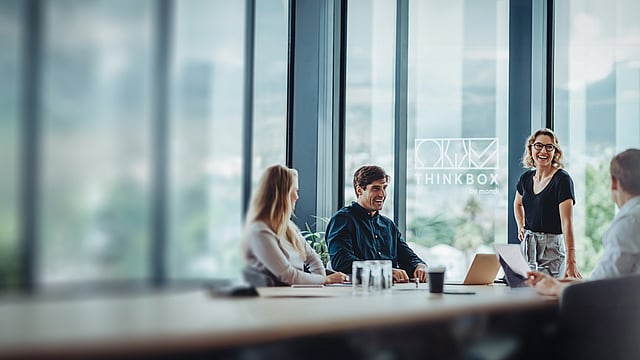 A group of people having a conversation around a table in a virtual ThinkBox space.